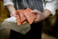 Close up of a fish mongerÃ¢â¬â¢s hands holding three fillets of fresh filleted salmon on a market stall in Yorkshire, England, UK Royalty Free Stock Photo